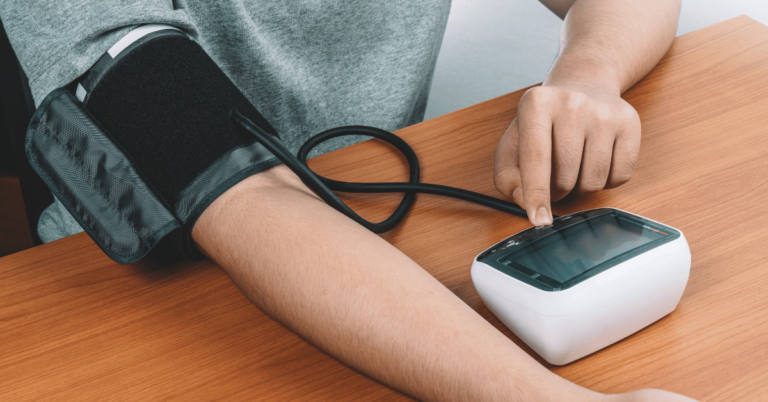 homem com medidor de pressão digital na mesa